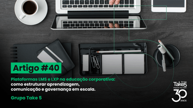 Vista superior de mesa de trabalho com notebook, café e materiais de escritório, ilustrando organização da aprendizagem em plataformas LMS e LXP para educação corporativa, com identidade visual do Grupo Take 5.