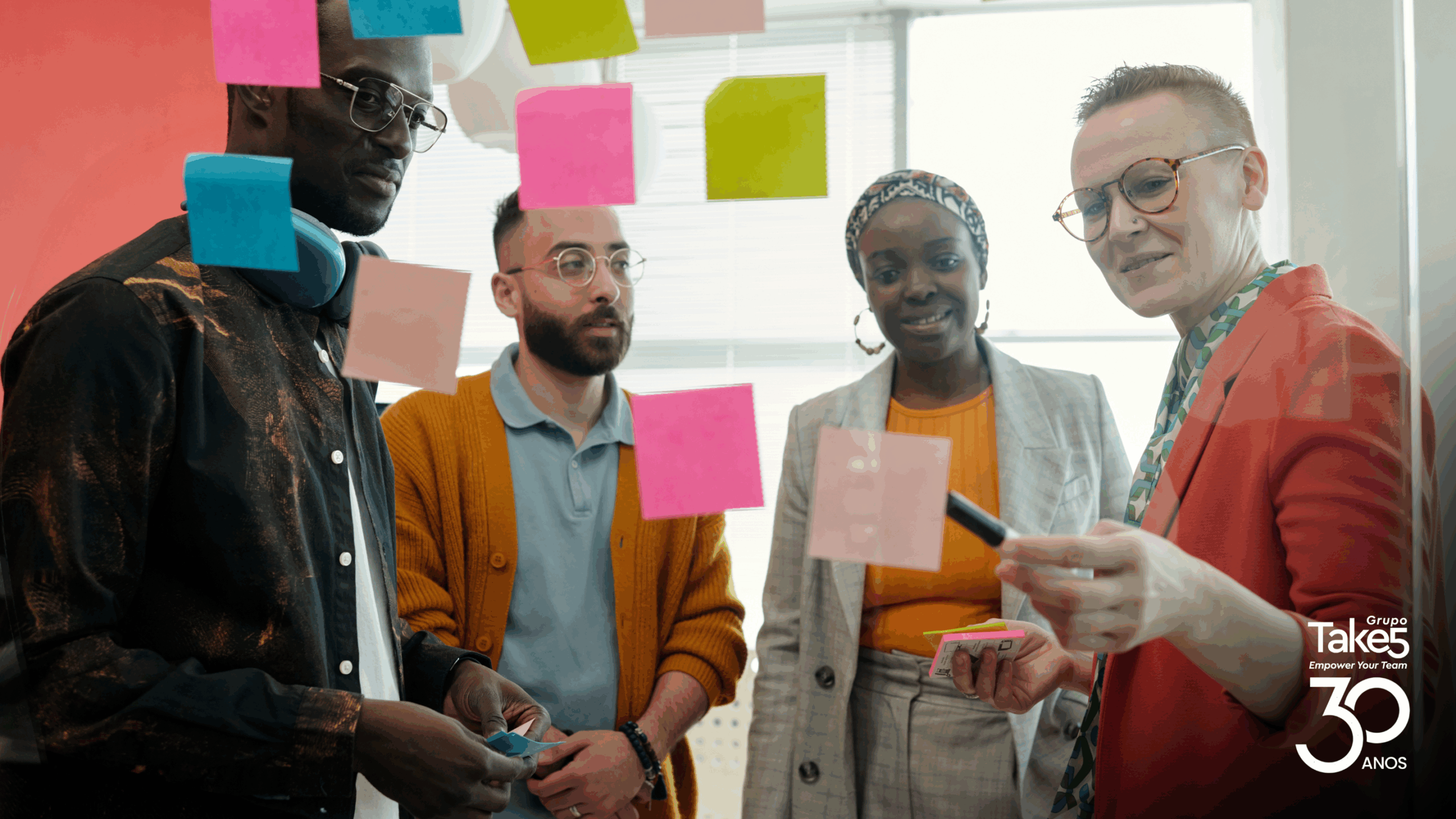 Grupo diverso de profissionais colabora em dinâmica com post-its, representando cocriação, aprendizagem colaborativa e inovação em programas de educação corporativa do Grupo Take 5.