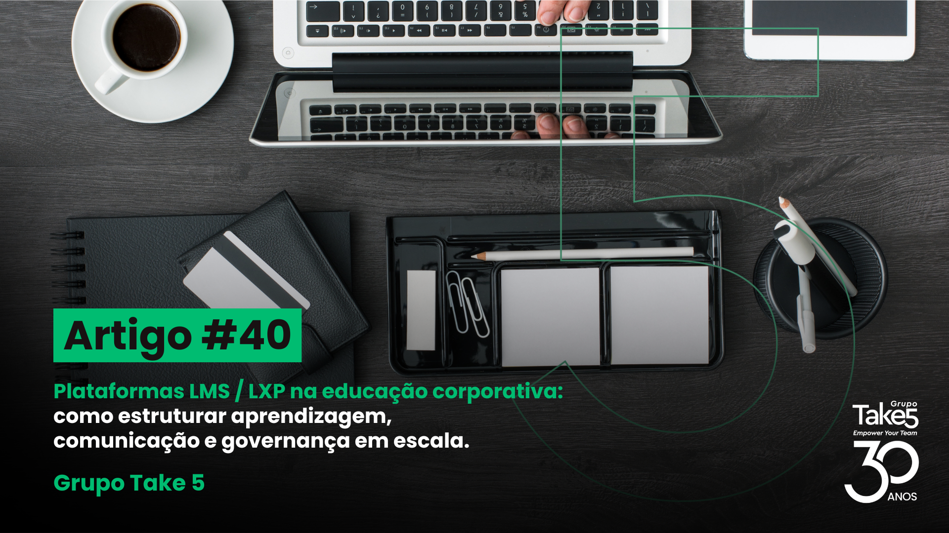 Vista superior de mesa de trabalho com notebook, café e materiais de escritório, ilustrando organização da aprendizagem em plataformas LMS e LXP para educação corporativa, com identidade visual do Grupo Take 5.